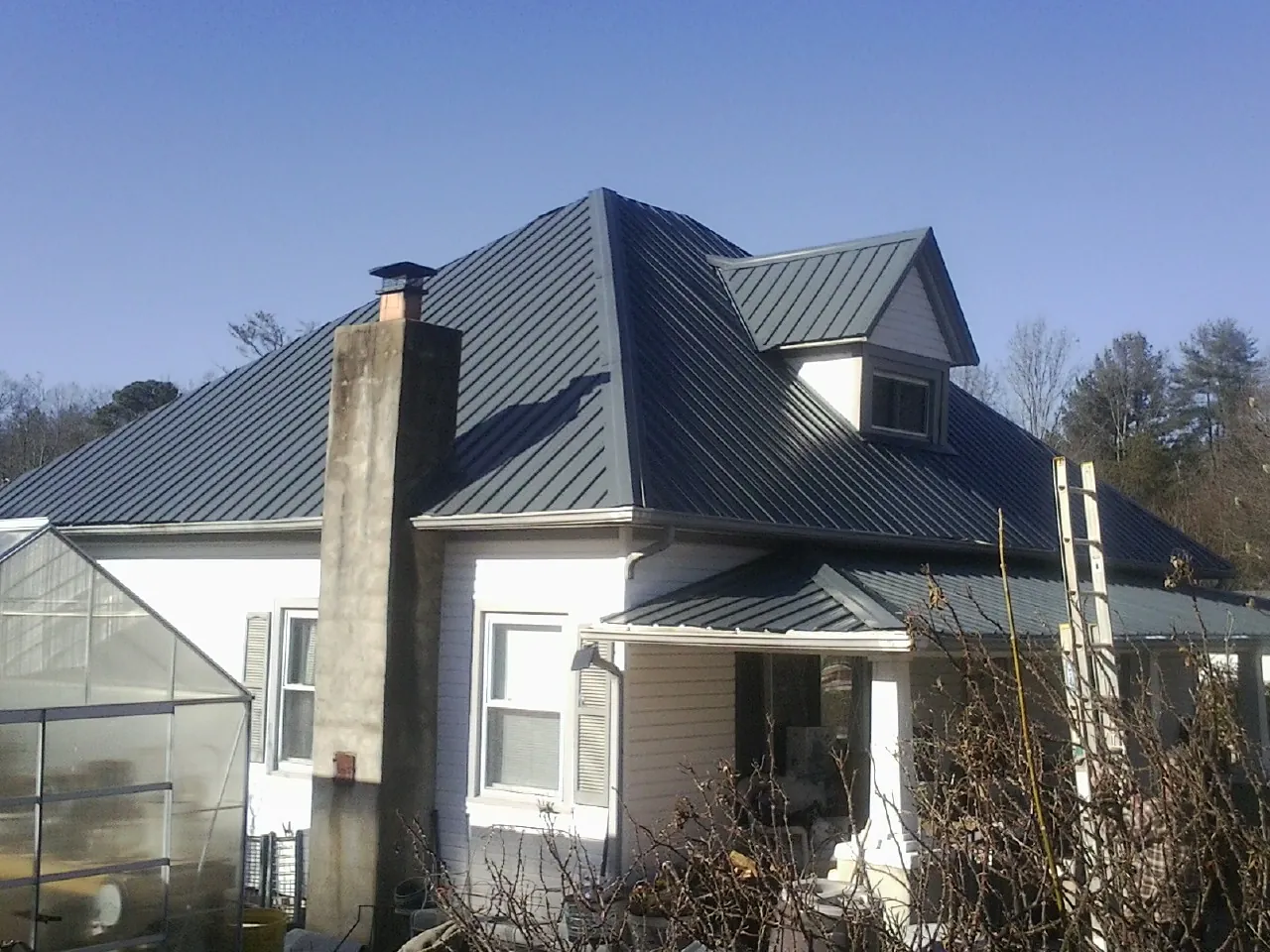 Dark blue standing seam metal roof on a white farmhouse with dormer — Slate & Tile Roof Repair by Roofing Brothers in Thorn Hill