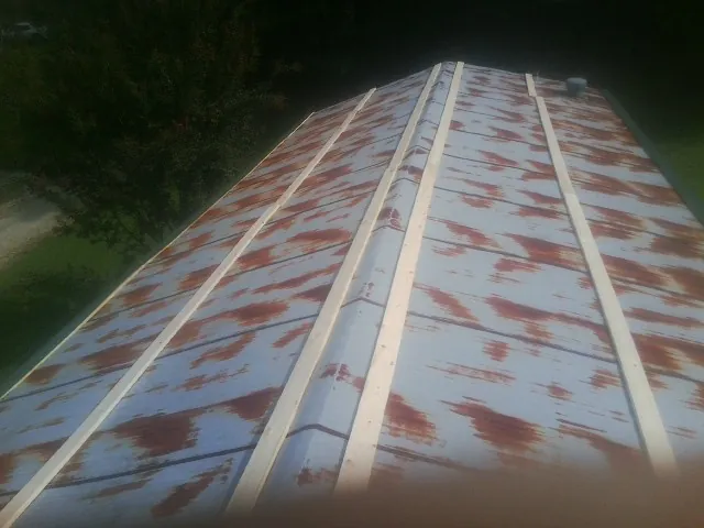 Rusted metal roof panels with new wood purlins before replacement — Storm Damage Roof Repair in Thorn Hill by Roofing Brothers
