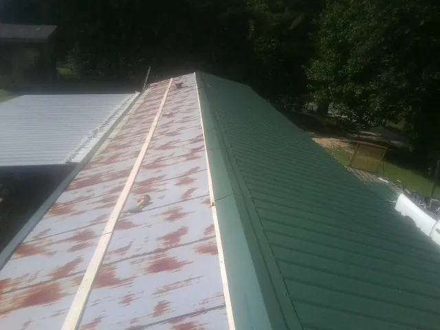 Old rusted panels beside newly installed green metal roofing — Wind Damage Roof Repair by Roofing Brothers in Thorn Hill