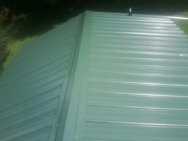 New green metal panels meeting at the ridge of a roof — Flat Roof Repair work by our crew in Thorn Hill
