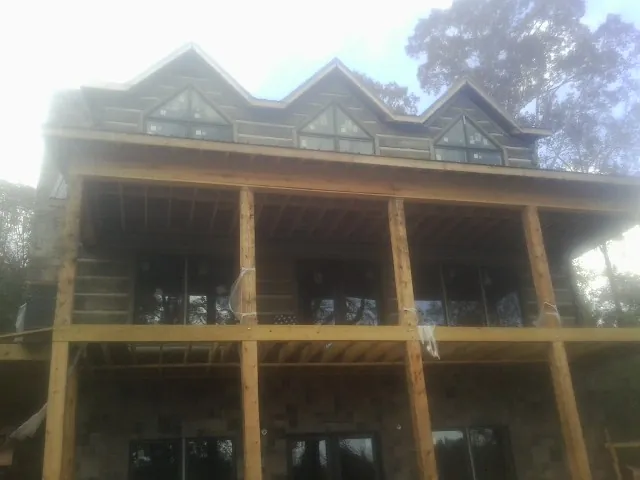 Dormers and porch framing on a large log home under construction — Roof Coating work by our crew in Thorn Hill