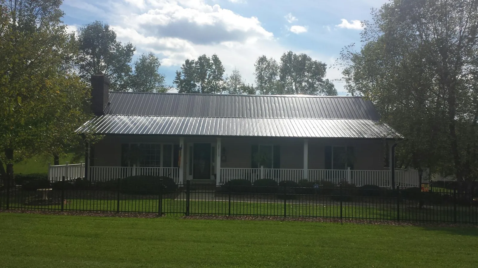 Gray metal roof on a brick ranch with a full width front porch — Gutter Guard Installation work by our crew in Thorn Hill