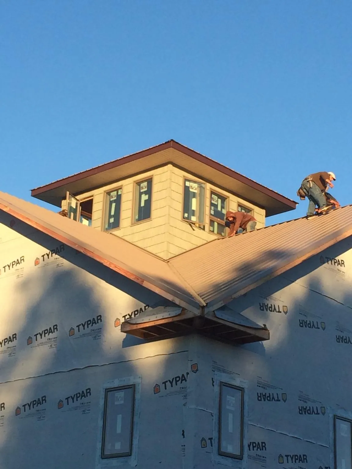 Roofers working around a rooftop cupola on a new metal roof at sunset — Roof Waterproofing in Thorn Hill by Roofing Brothers